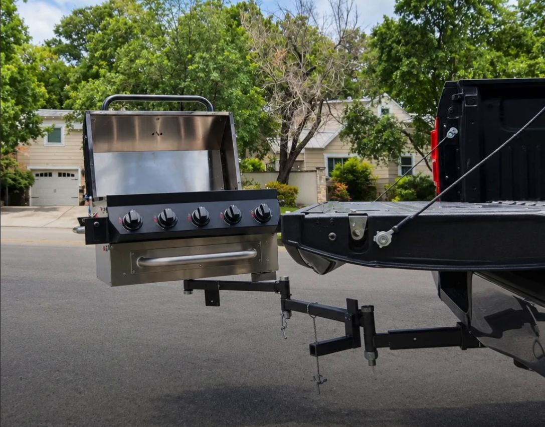 GrillGate hitch-mounted grill swung out behind a truck at dusk